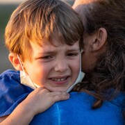 Un enfant pleure dans les bras de sa mère.