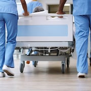 Des membres du personnel d'un hôpital transportent un patient sur une civière.