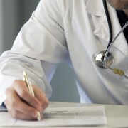 Un médecin écrit sur un papier. 