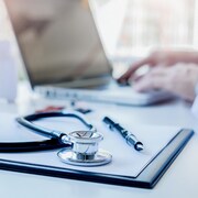 Un stéthoscope et un médecin utilisant un ordinateur portable.