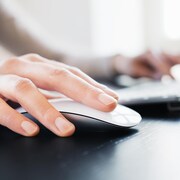 Une personne utilise une souris et un clavier d'ordinateur.