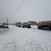 Des véhicules de police, gyrophares allumés, bloquent une rue d'un village. 