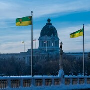 Des drapeaux saskatchewanais devant le Palais législatif de la Saskatchewan en hiver à Regina.
