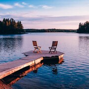 Deux chaises vides sur une plateforme flottante sur un lac au coucher du soleil.