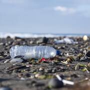 Une bouteille d'eau en plastique parmi des ordures sur une plage.