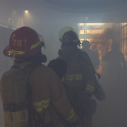 Des pompiers avancent dans la fumée. 