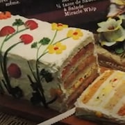 Un pain-sandwich à quatre étages avec un glaçage décoré de fleurs.
