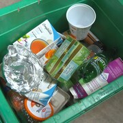 Une boîte verte contenant divers emballages recyclables.