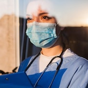 Une travailleuse de la santé avec un stéthoscope autour du cou porte le masque sanitaire. 