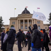 Des membres de la Fédération des enseignants de la Saskatchewan (STF) manifestent devant le Palais législatif, le 20 mars 2024.