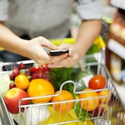 Une personne qui utilise un téléphone mobile en faisant une épicerie.