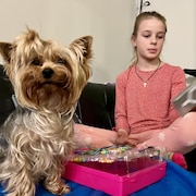 Une fillette assise sur un sofa avec sa chienne. 