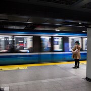 Une femme attend l'arrivée du métro sur le quai.