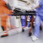 Photo d'infirmiers en mouvement poussant une civière dans un couloir.