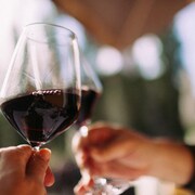A man holds a glass of red wine.
