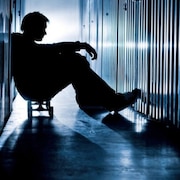 Un jeune homme assis entre des casiers souffre de santé mentale