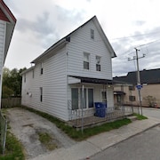 Une maison allumette blanche sur le coin d'une rue.