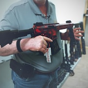 Un homme tient une arme prohibée dans ses mains.