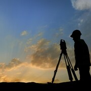Un arpenteur-géomètre de profil en fin de journée.