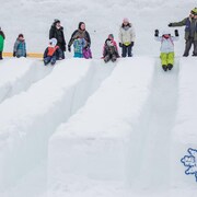 Des enfants qui glissent sur une montagne de neige.