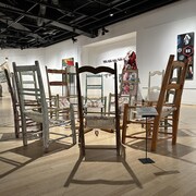 Des chaises placées en cercle dans une galerie d'exposition.