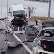 Scène d'accident sur une autoroute avec un camion et deux voitures accidentés.