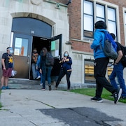 Des élèves masqués entrent dans une école.