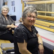 Deux femmes sourient devant une couverture. 