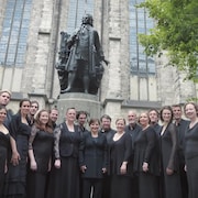 Un groupe de personnes qui posent devant une statue du compositeur Jean-Sébastien Bach.