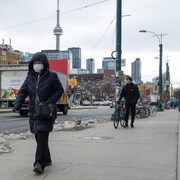 Une femme portant un masque sanitaire marche dans une rue du quartier chinois de Toronto.