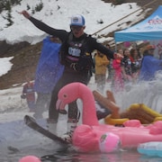 Skieur tentant de traverser un étang au travers de jouets gonflables. Mai 2024.