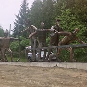 Une grande sculpture représentant la Chasse-Galerie sur le bord d'une forêt.