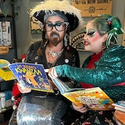 Deux drag queens regardent des livres pour enfants ensemble.