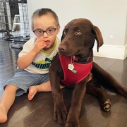 Un jeune garçon assis sur le sol aux côtés d'un chien.