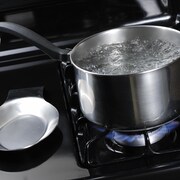 De l'eau qui bout dans une casserole sur un four.