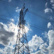 Plan contreplongé d'une charpente en métal avec en arrière plan un ciel bleu et quelques nuages blanc (septembre 2023).