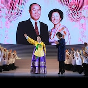 Hak Ja Han Moon sur une scène au milieu d'enfants brandissant les bras vers le ciel.