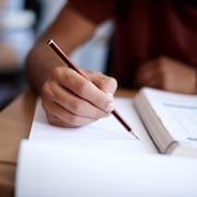 Un étudiant assis a un pupitre écrit un examen.