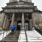 La famille monte les marches de l'hôtel de Ville sous les flocons de neige. 