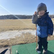 Un petit garçon avec un bâton de golf. 