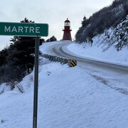 une route enneigée à La Martre, avec le panneau d'indication d'entrée au village.
