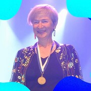 Une femme qui sourit avec une médaille autour du cou.