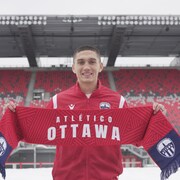 Manny Aparicio tient un foulard aux couleurs de l'Altético Ottawa.