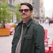 Homme portant des verres fumés regardant droit vers le photographe.