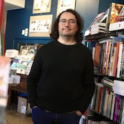 Un homme qui pose dans une allée d'une librairie.