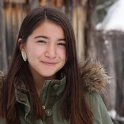 Une fille devant un mur en bois à l'extérieur en hiver.