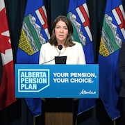 Danielle Smith qui parle au podium entourée de Jim Dinning et Nate Horner, le 21 septembre 2023.