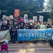 Des membres de la Nation Nuchatlaht sur les marches de la cour suprême de la Colombie-Britannique avec des banderolles.