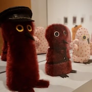 Des œuvres représentant de petites créatures dans une salle d'exposition.