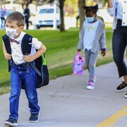 Deux enfants masqués marchent pour se rendre à l'école.